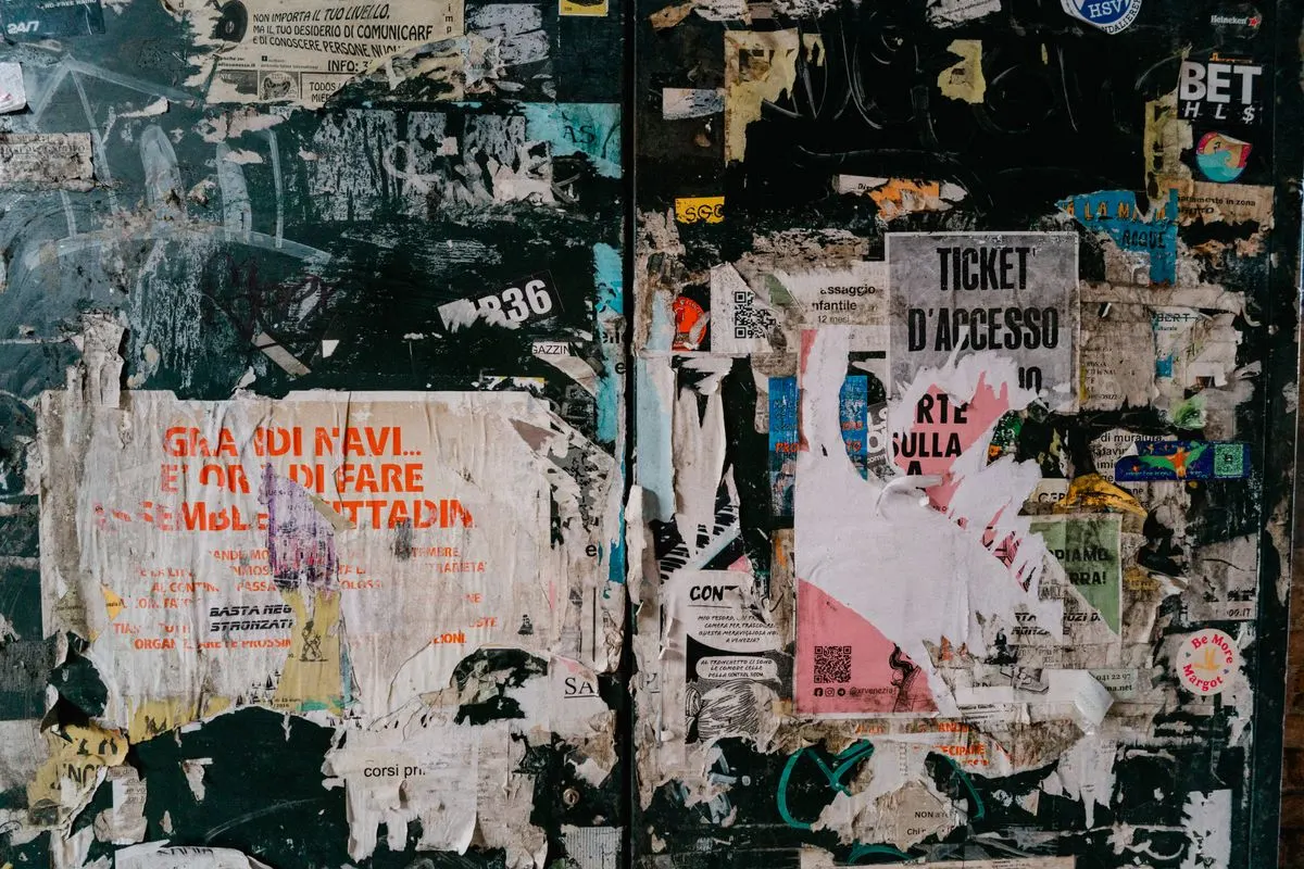A wall of weathered, layered posters on a city street